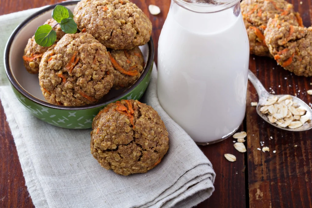 Soft Carrot Cake Cookies Recipe served in a bowl with a bottle of milk and a spoonful of oats, perfect for a Carrot Cake recipe.