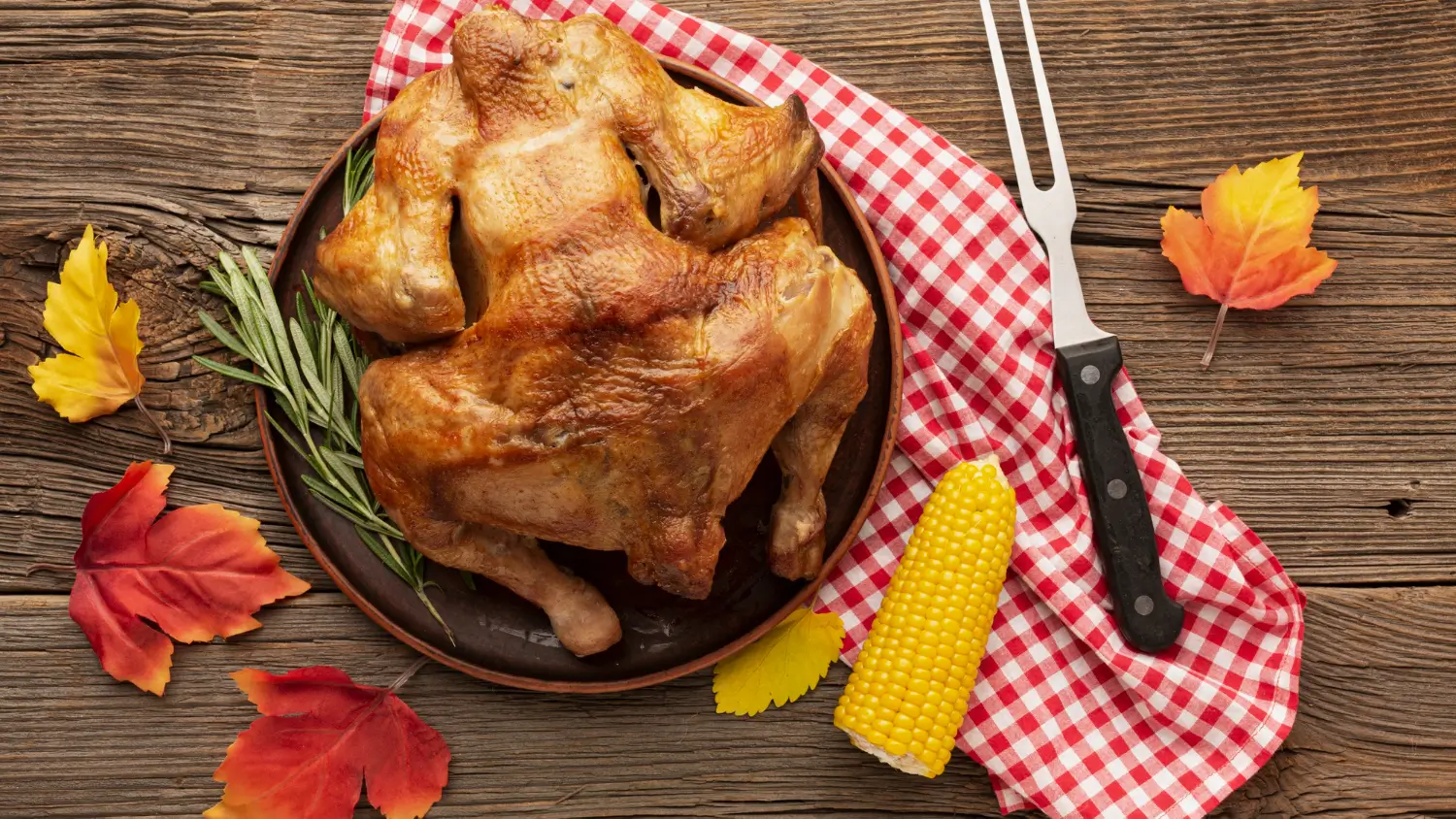 Golden roasted turkey with rosemary on a rustic plate, paired with corn and fall leaves, ideal for Smothered Turkey Wings recipes.